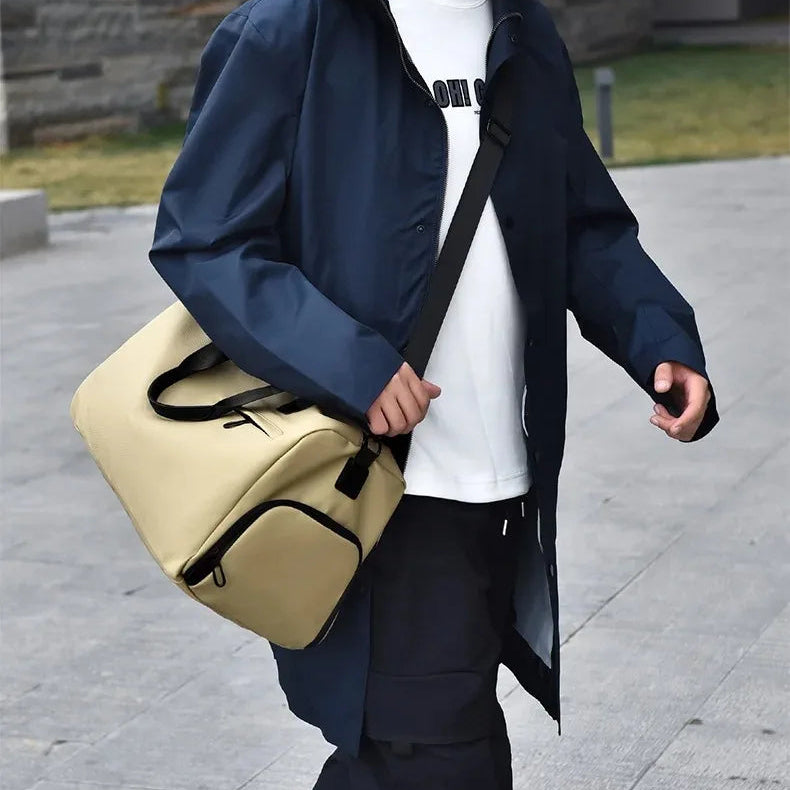 Man walking outdoors carrying a beige tactical messenger bag with black trim