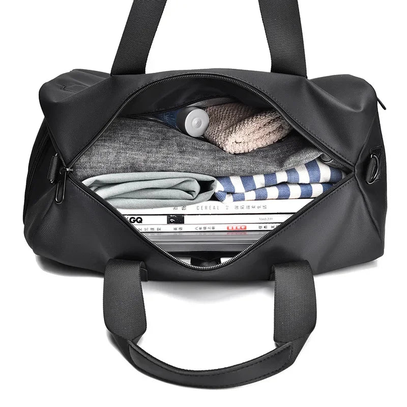 Open black duffel bag neatly packed with clothes, a magazine, and a bottle for travel